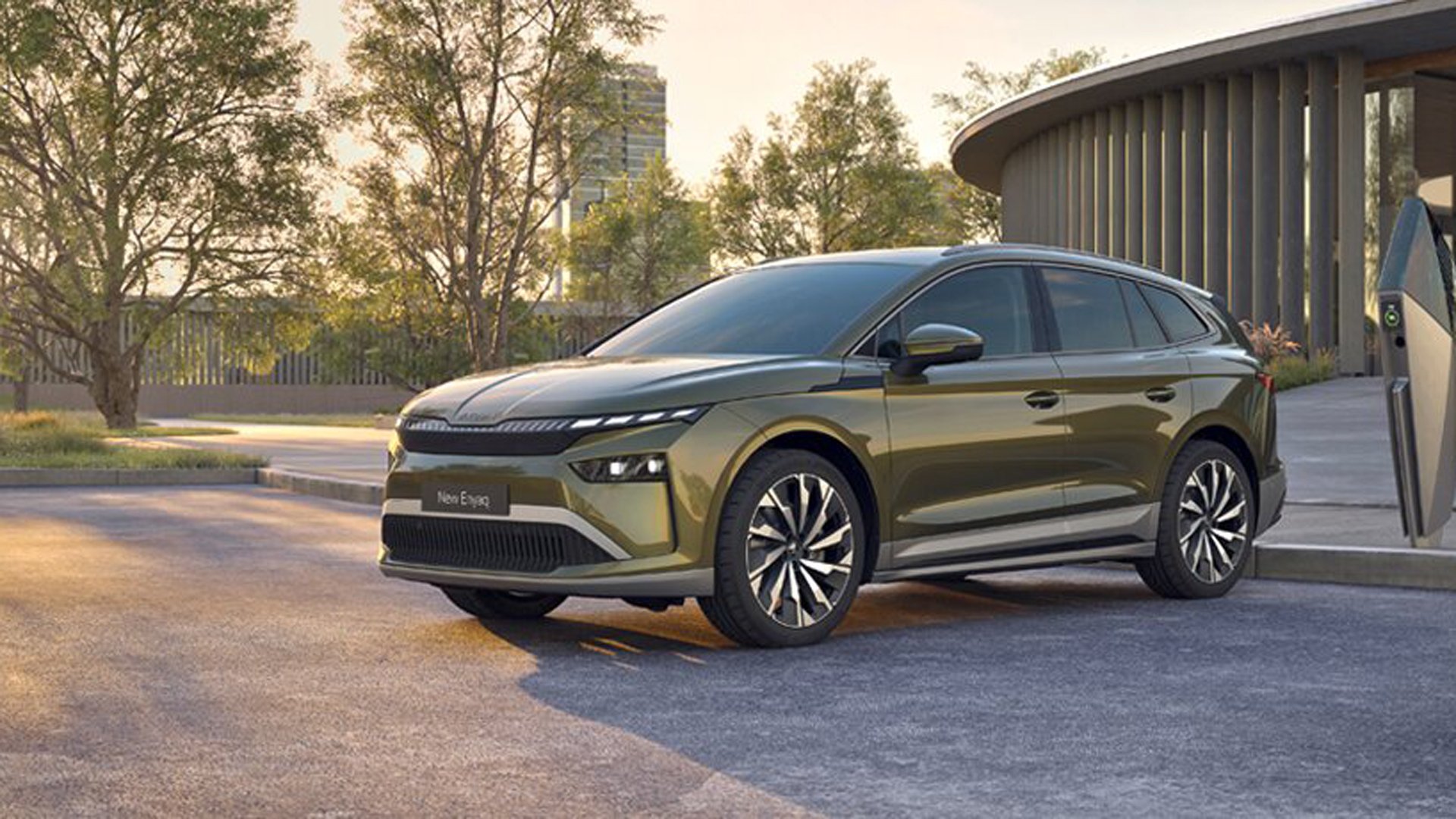 Skoda Enyaq parkert med en ladestasjon foran en park