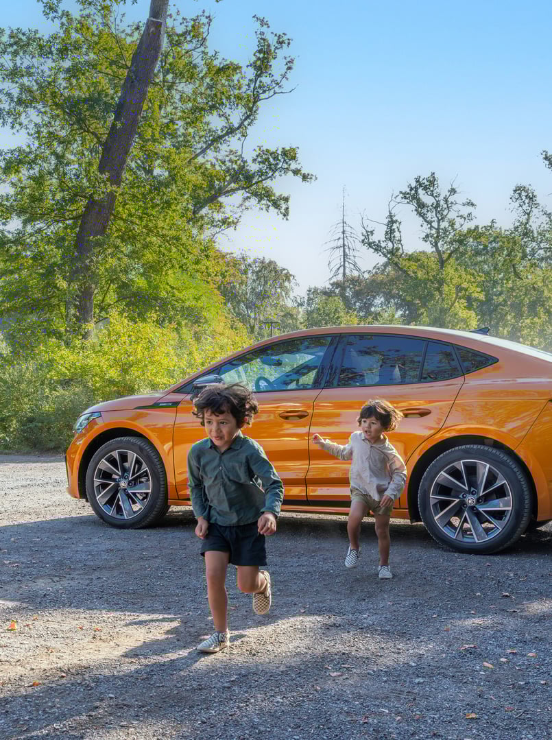 To barn løper utenfor en Skoda Enyaq Coupe