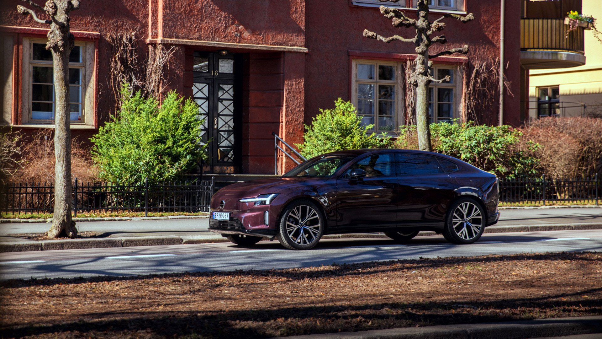 En Volvo ES90 parkert foran et rødt murhus