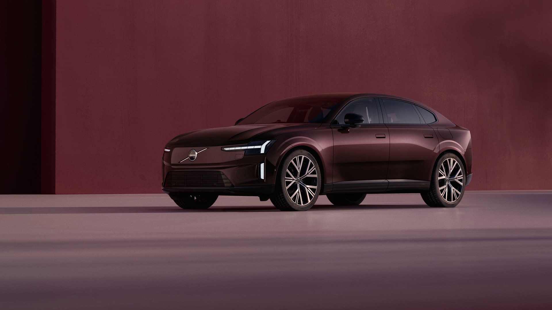 Volvo ES90 i Mulberry red parkert foran en vegg i tilsvarende farge