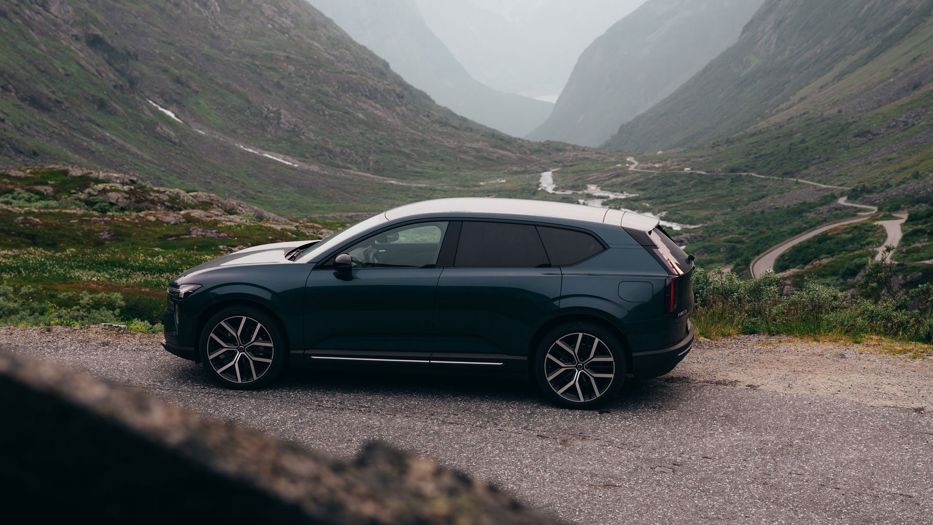 Volvo EX60 sett fra siden med spektakulær utsikt med dype daler og svingete veier
