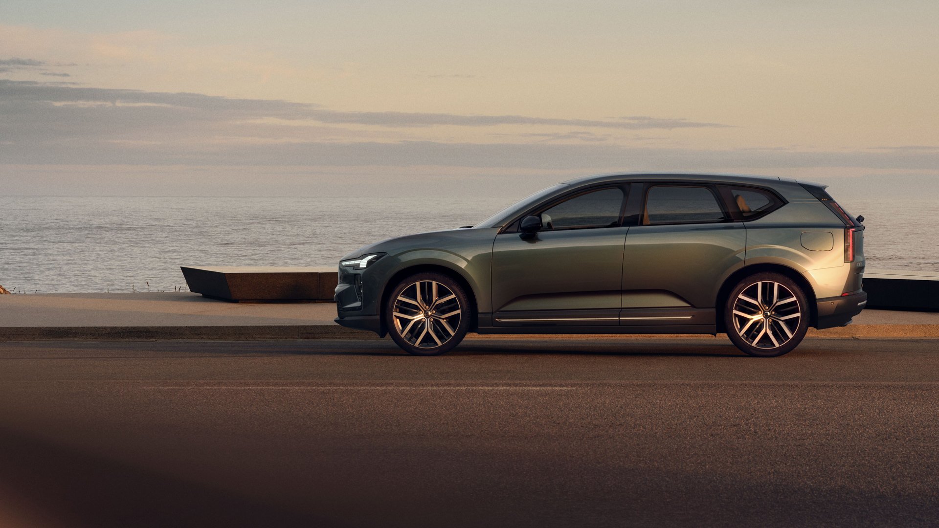 En Volvo EX60 sett fra siden stående med et vann i bakgrunnen