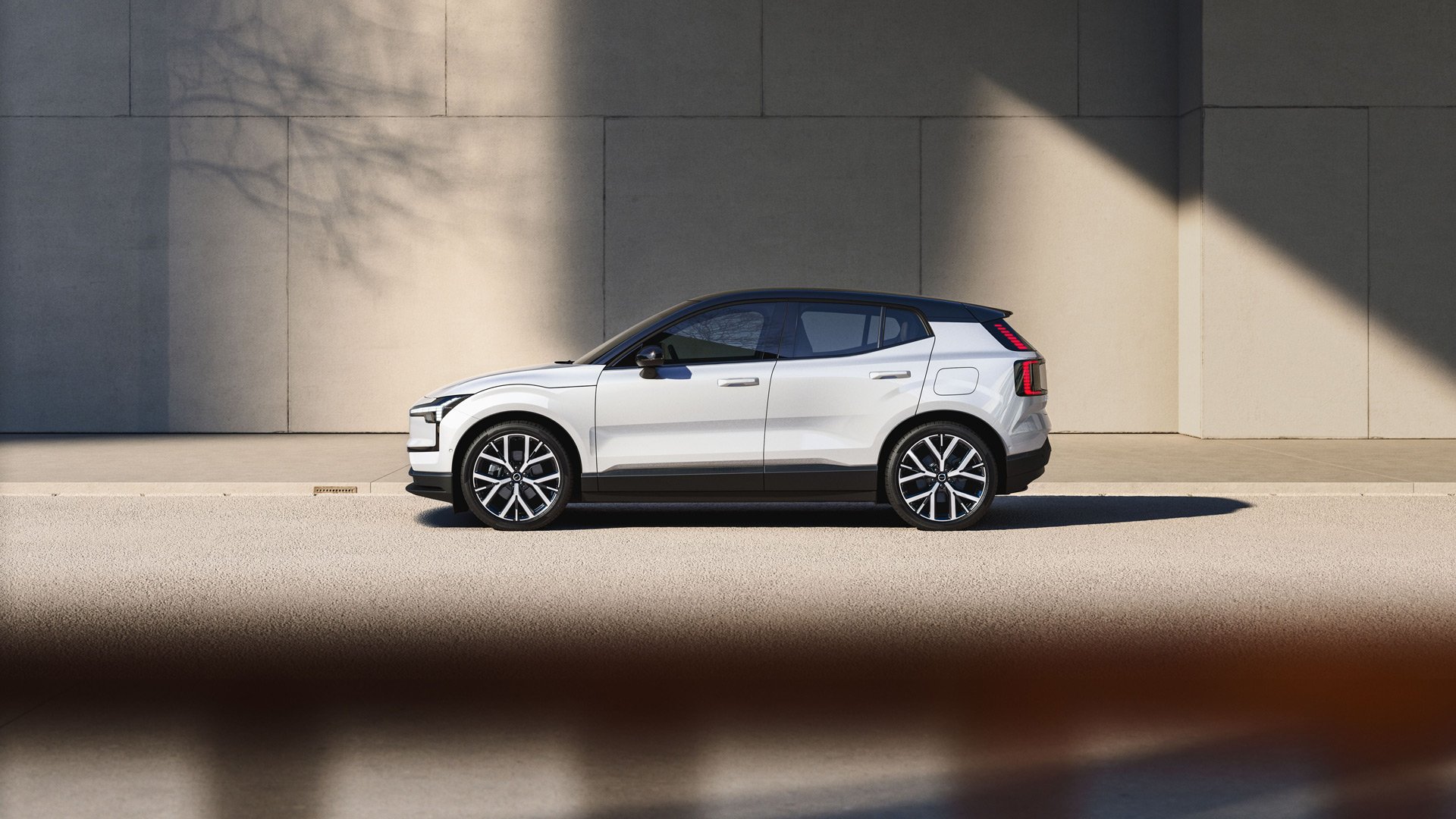 En hvit Volvo EX30 sett fra siden i et urbant miljø