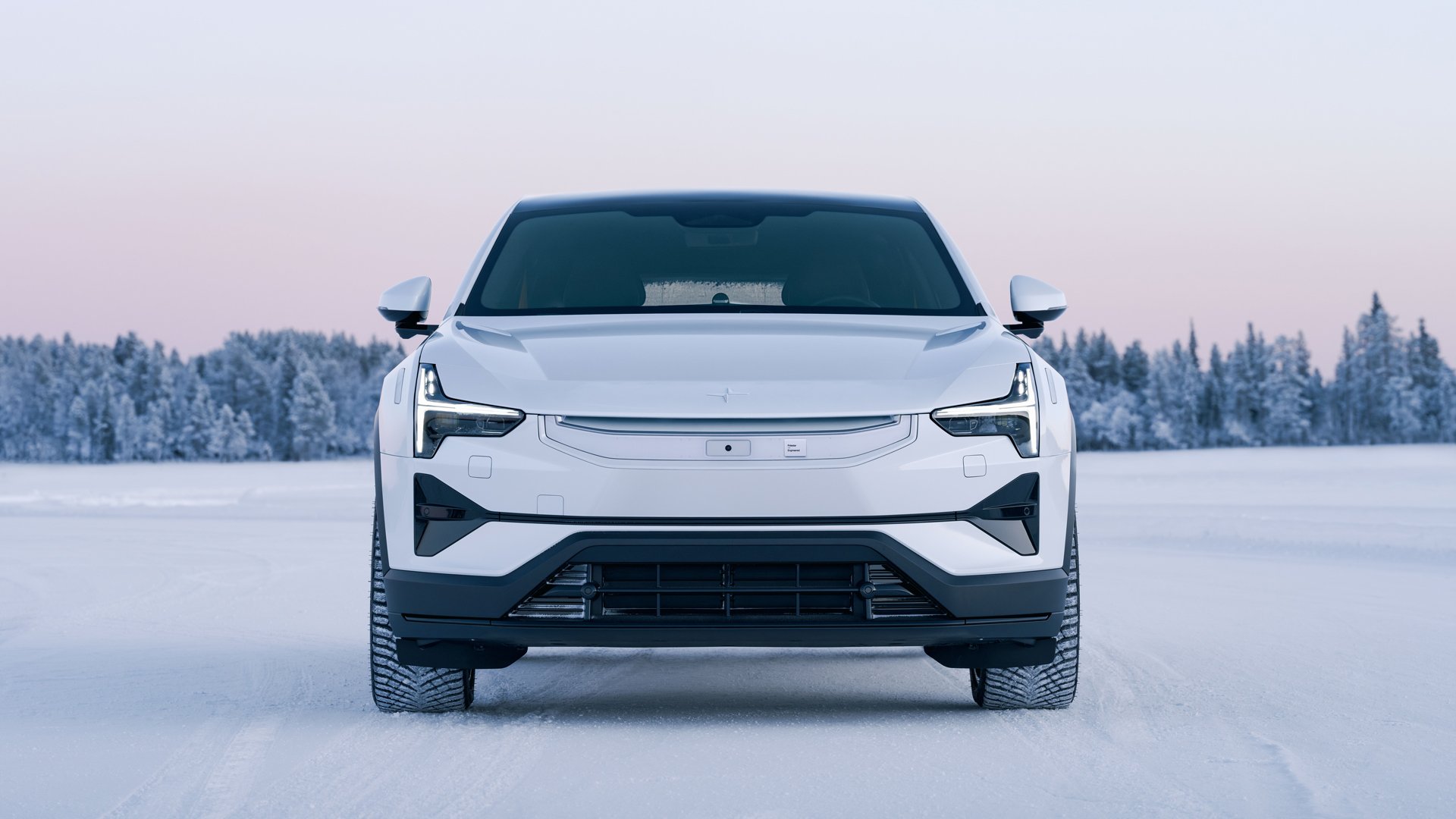 En Polestar 3 stående i et snødekket landskap med snødekte trær i bakgrunnen, med flott vinterhimmel