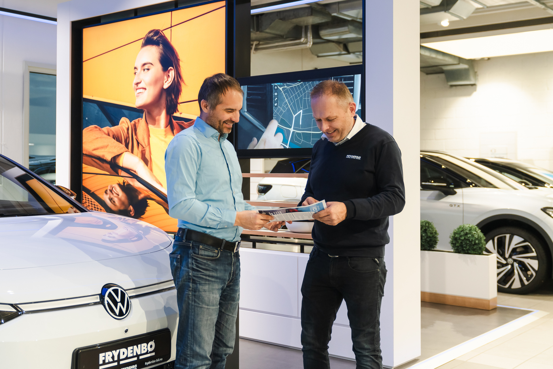 En selger og kunde går over noen papirer hos Frydenbø Bil