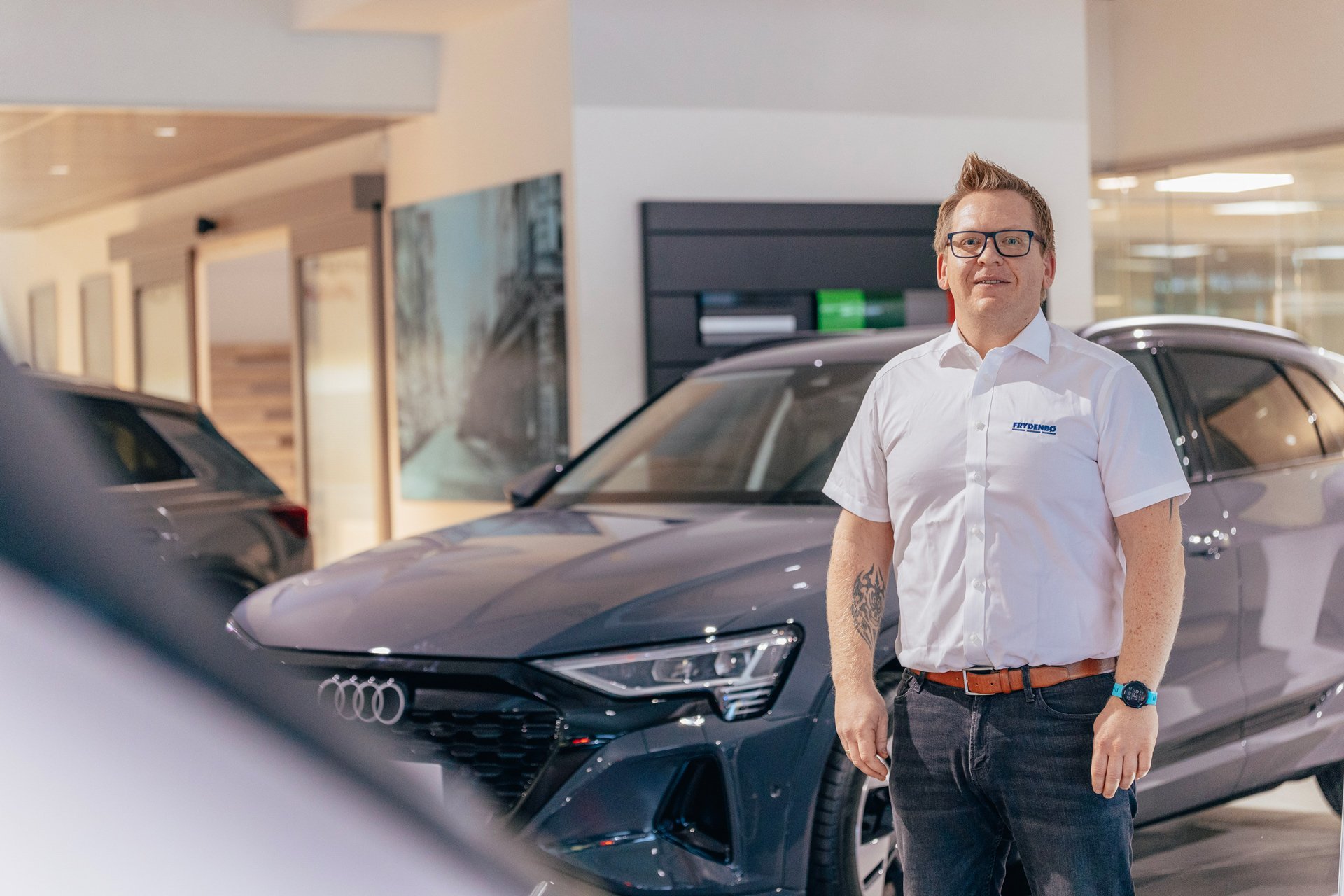 Smilende bilselger hos Frydenbø Bil Førde med Audi i bakgrunn og forgrunn.