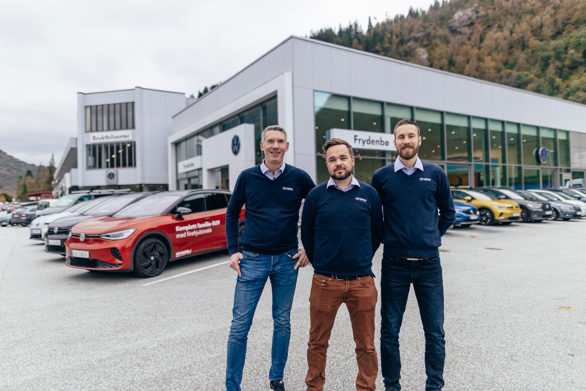 Smilende bilselgere utenfor Frydenbø Bil Førde med Volkswagen, Audi og Škoda i bakgrunnen