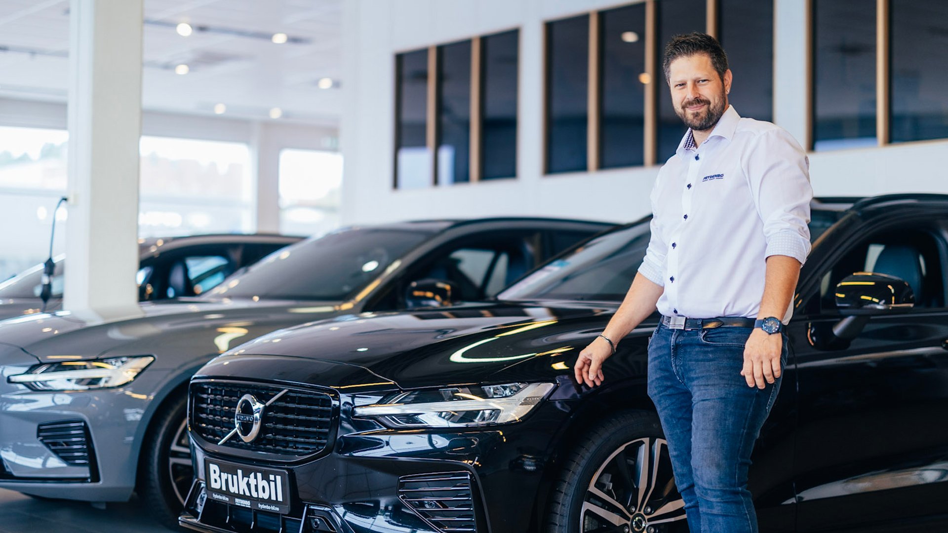 En bruktbilselger står sammen med en brukt Volvo hos Frydenbø Bil i Kristiansand
