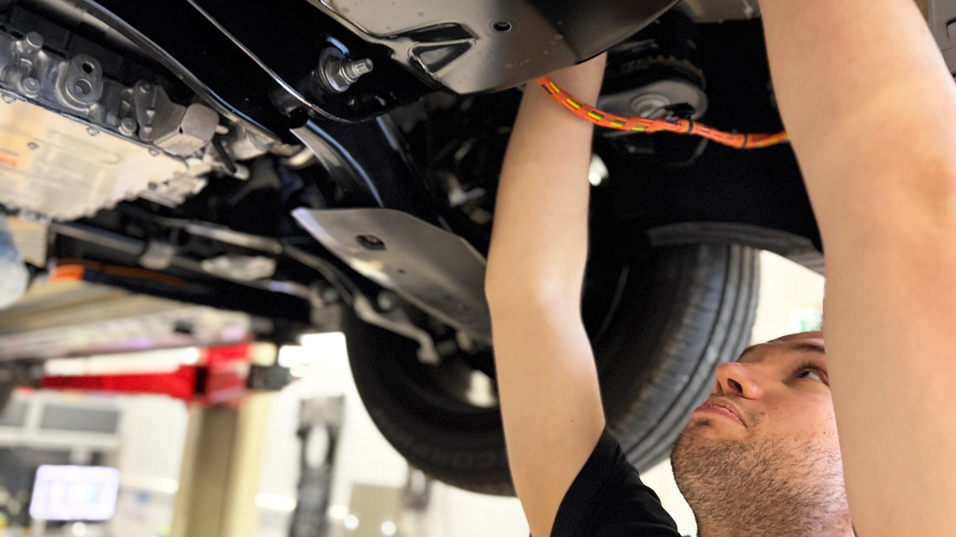 En mekaniker hos Frydenbø Bil Sogndal jobber under en bil på verkstedet