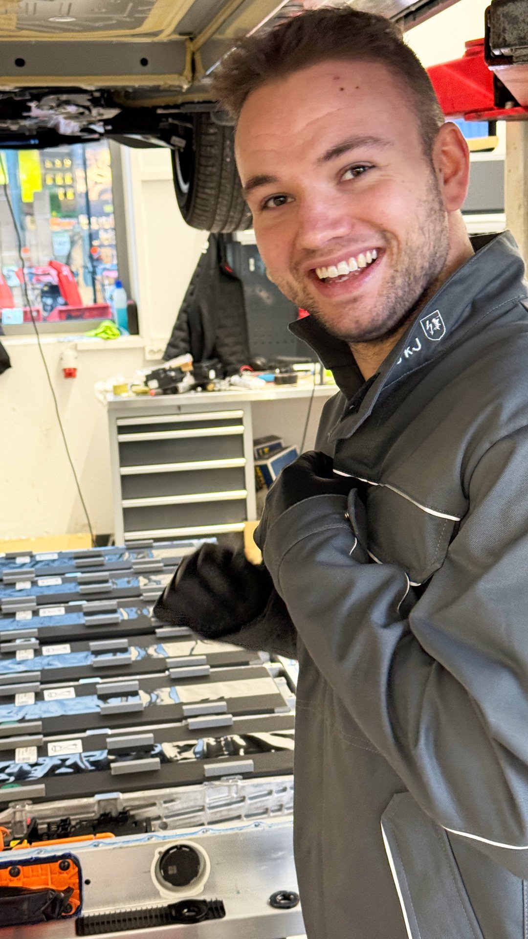 En smilende mekaniker hos Frydenbø Bil Sogndal foran en batteripakke