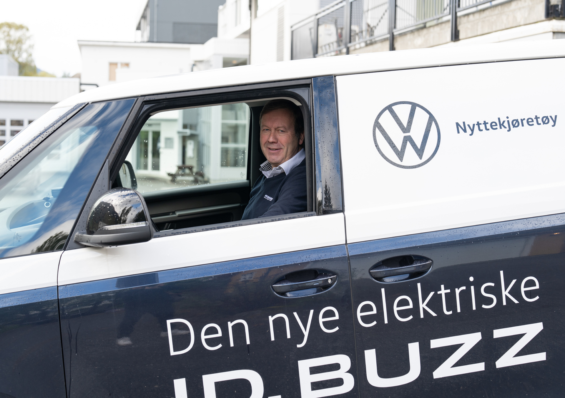 En smilende bilselger sittende i en ID Buzz