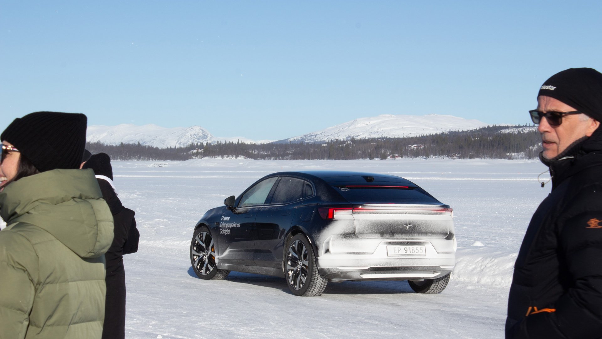 En Polestar 4 parkert på isen dekket i snøsprut blant kunder