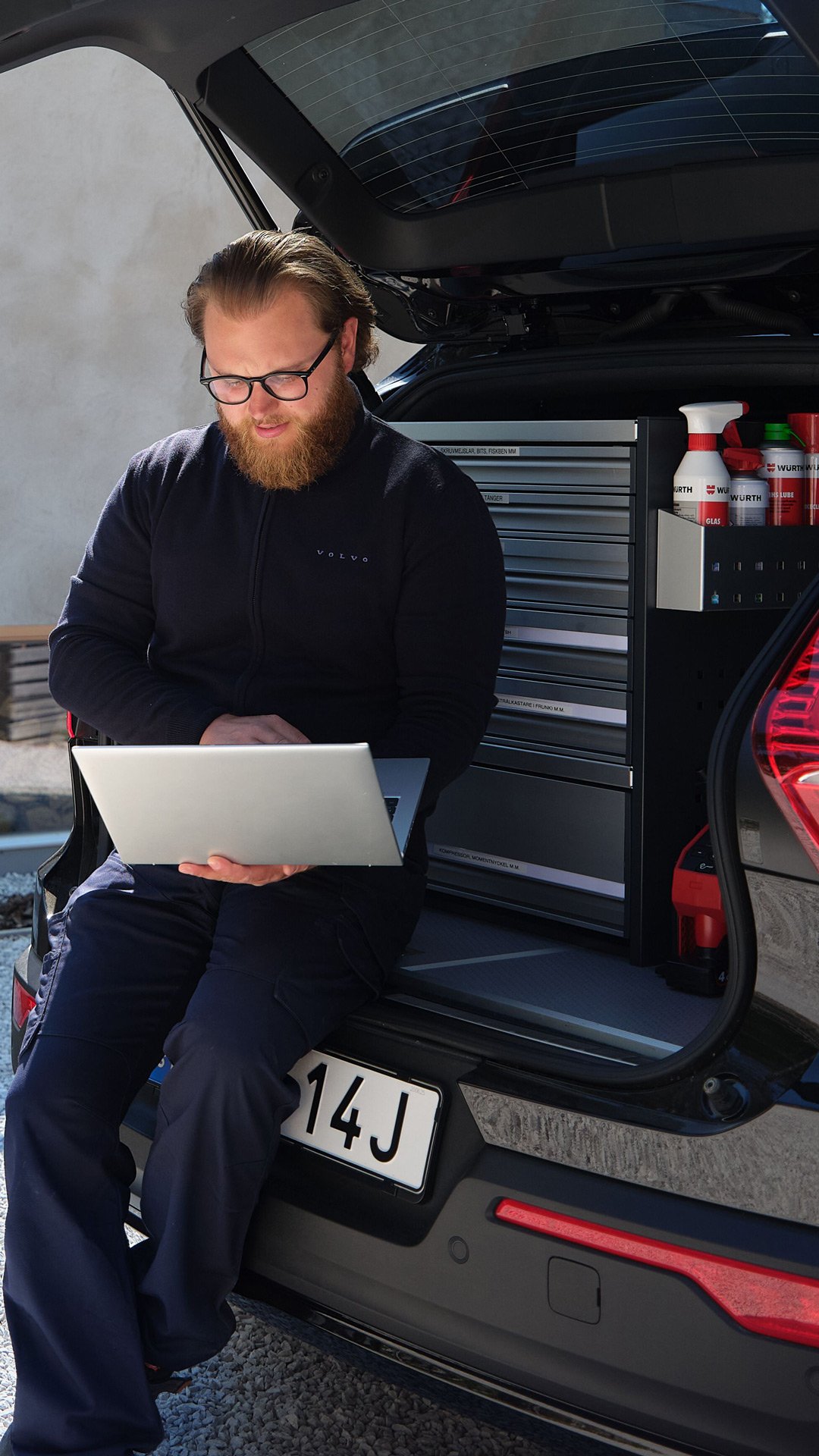 En tekniker sitter i bagasjeromsluken på sin Mobile Service bil