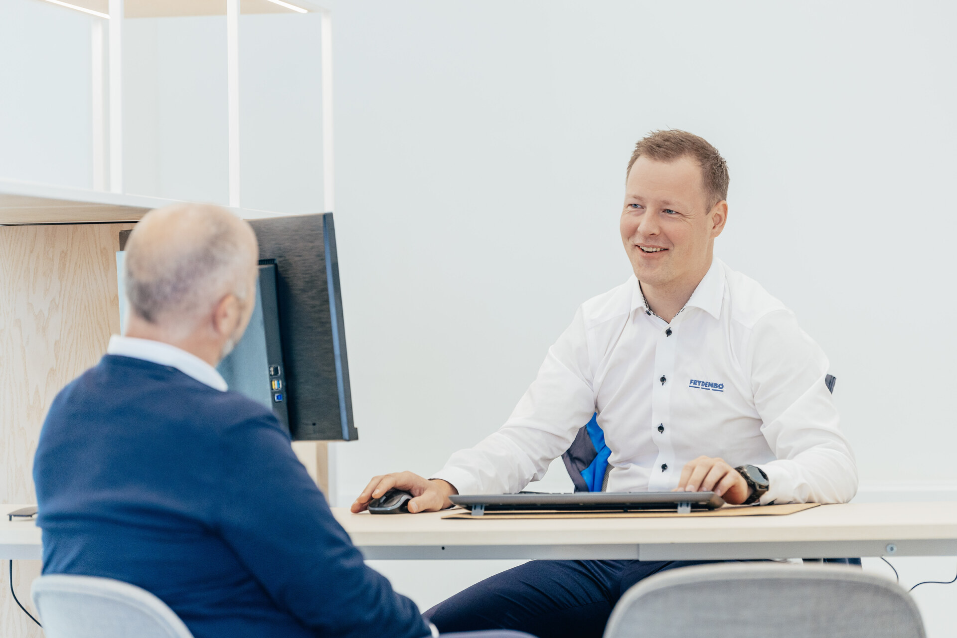 En Frydenbø ansatt sitter sammen med en kunde på en pult