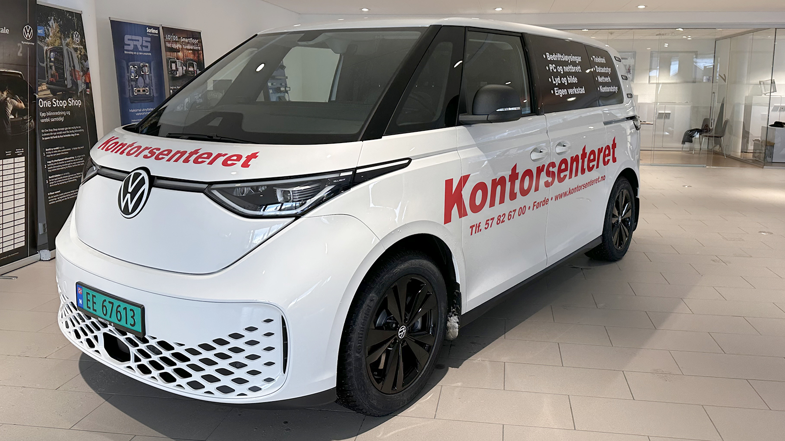 En Volkswagen ID Buzz står utstilt i lokalene til Frydenbø Bil, den har rød reklame og bilen er hvit