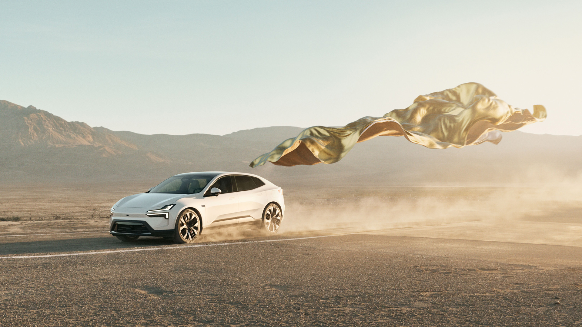 En polestar 4 kjørende i ørkenen, med et gull teppe flyvende bak