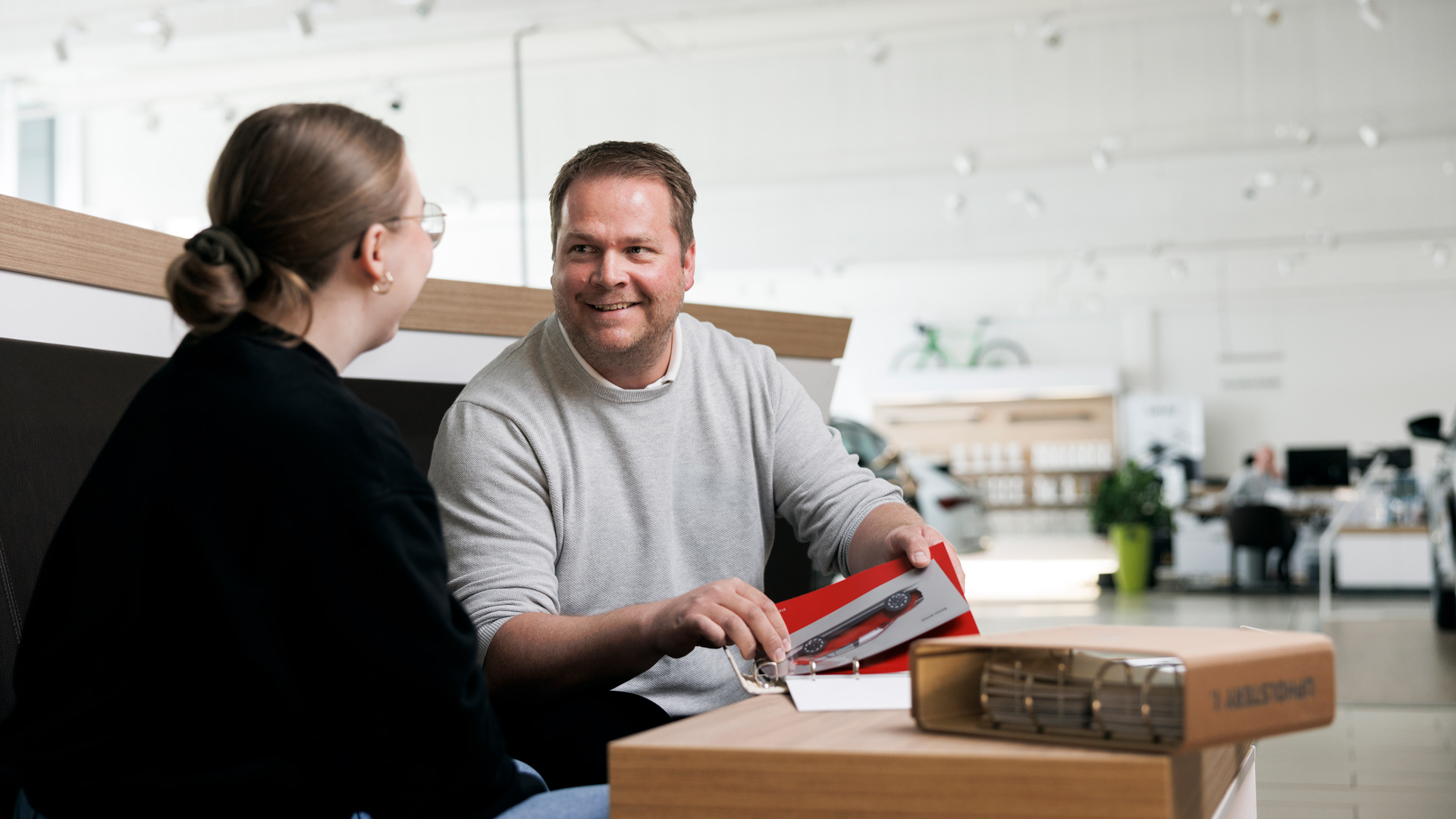 En selger sitter sammen men kunde og går gjennom tilpasningsmuligheter på en bil