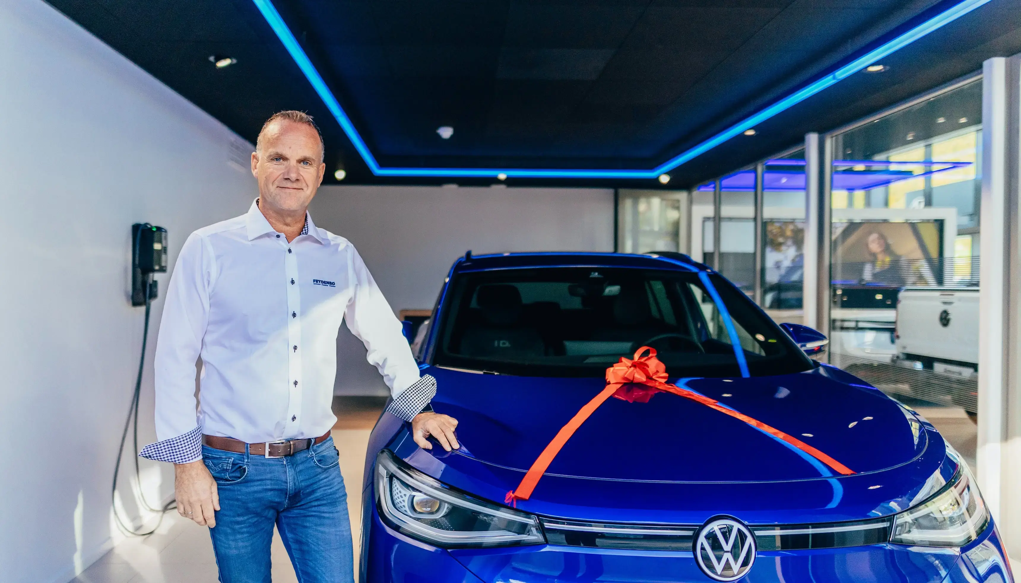 Kjetil Nesse hos Frydenbø Bil i Sogndal sammen med en blå Volkswagen som skal leveres til kunde