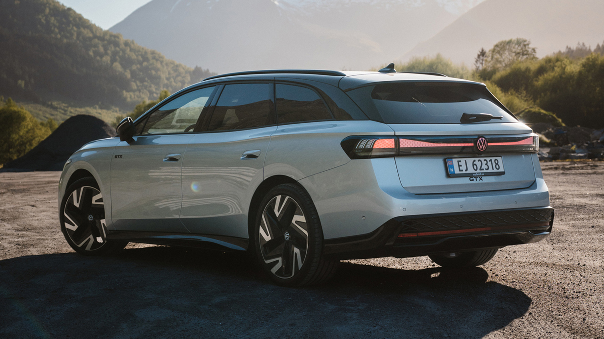 Volkswagen ID.7 vendt mot venstre med flott, norsk natur i bakgrunnen. Bilen kaster lang skygge til høyre med solen tydelig nedgående på høyre side bak fjellene.